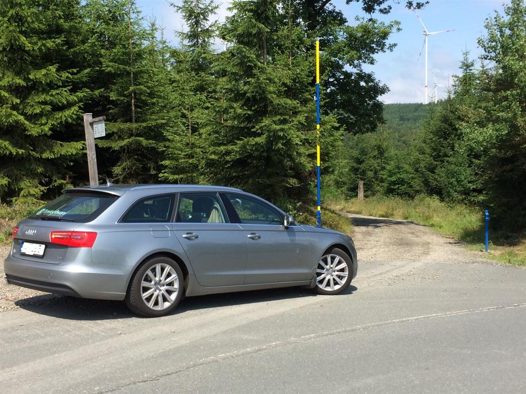 Das Bild zeigt einen Audi A6 am Straßenrand in waldlicher Umgebung
